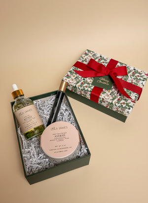 Packaged gift set of Astrid Body Oil, Fragrance, and body butter bar on neutral background.