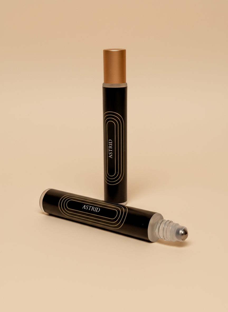 Two black cylindrical containers with gold caps on a tan background, branded 'ASTRID'.