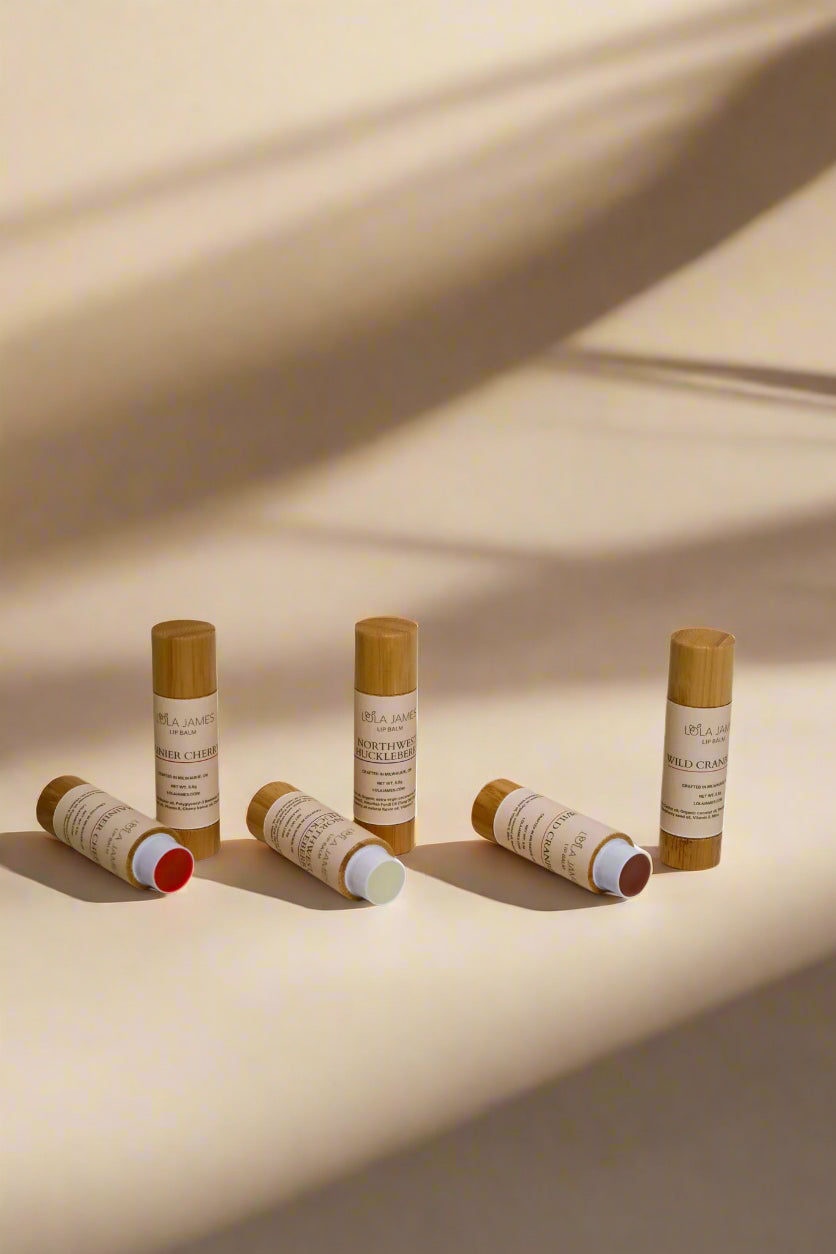 6 small cylindrical lip balm containers with bamboo packaging on a beige background