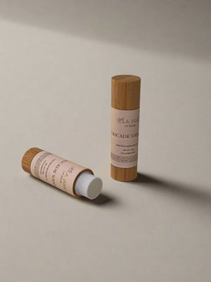 2 lip balms in bamboo containers on a beige background.