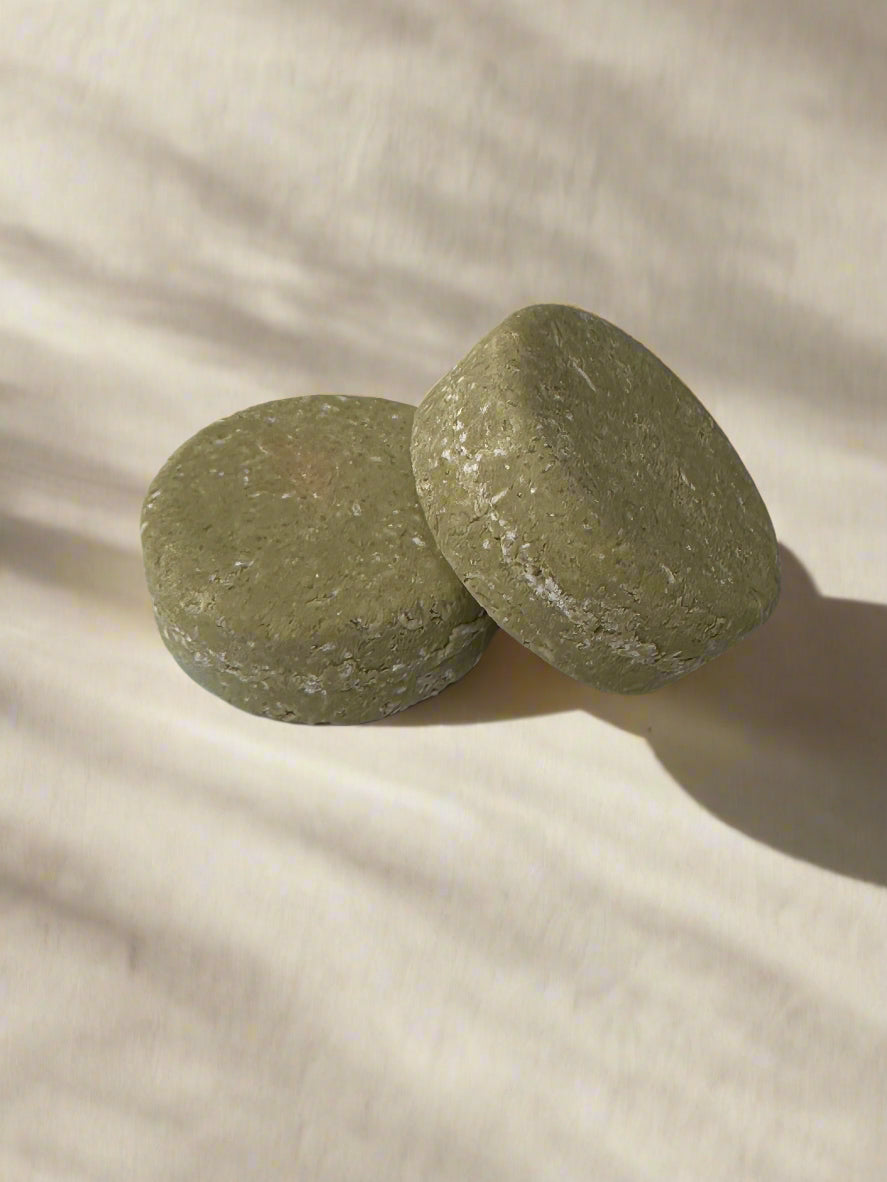 2 green shampoo bars stacked, beige background.
