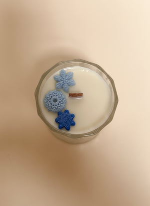 Candle with decorative blue snowflakes on a cream background