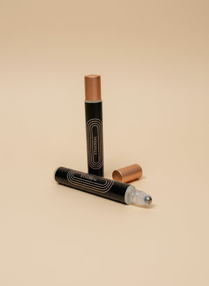 Two black cosmetic tubes with gold caps on a tan background
