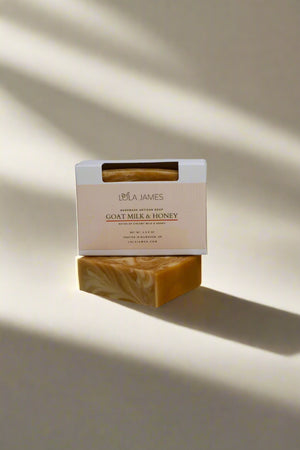 Bar of gold and cream swirled soap with a box labeled 'Lola James' on a white background