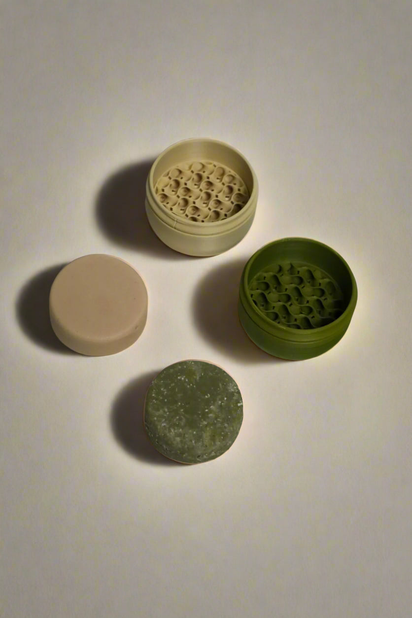 Green shampoo bar, green travel case, beige conditioner bar, beige travel case on light background.