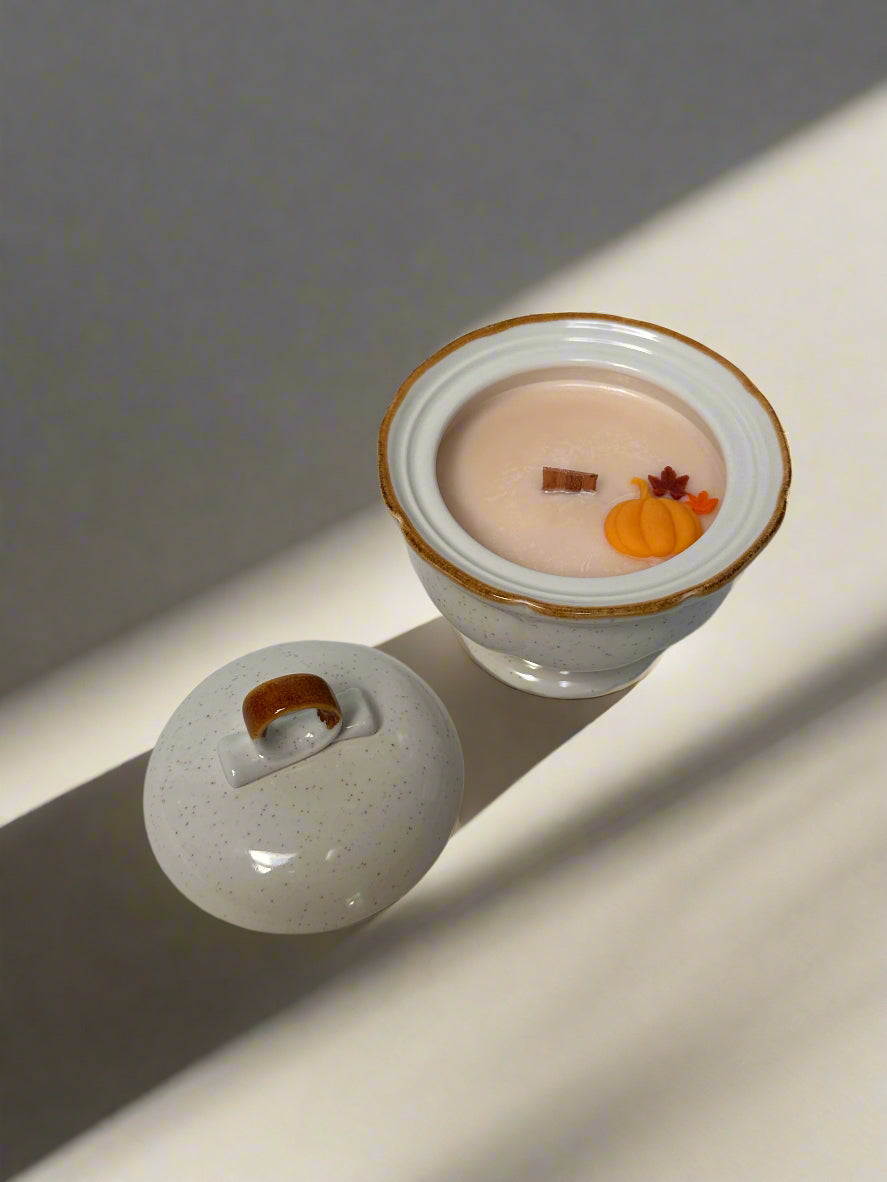 Stoneware sugar bowl containing soy candle with pumpkin and leaf embeds on a neutral background.