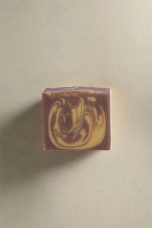 Swirl patterned purple and cream colored soap bar on a plain background
