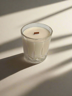 Glass candle with a wooden wick on a light background