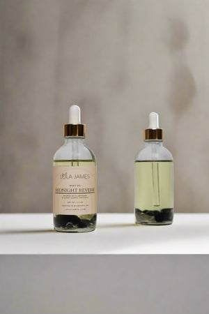 Two bottles of Lola James body oil on a beige background
