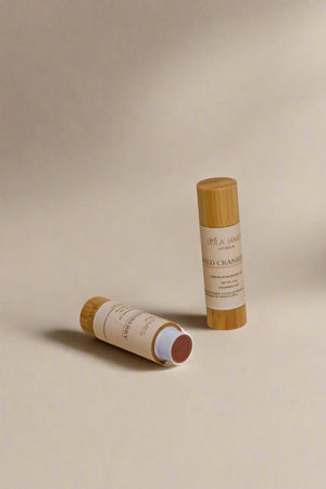 Two bamboo lip balm sticks on a beige background