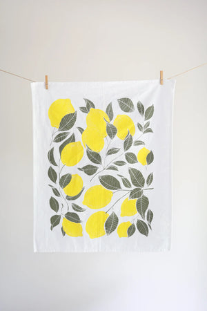 Tea towel with lemon design hanging on a line against a white wall