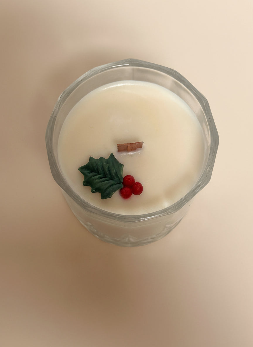 Candle with holly berry a wooden wick on a cream background