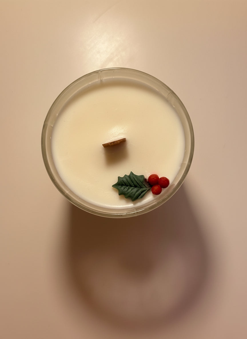 Candle with decorative holly elements on a plain background