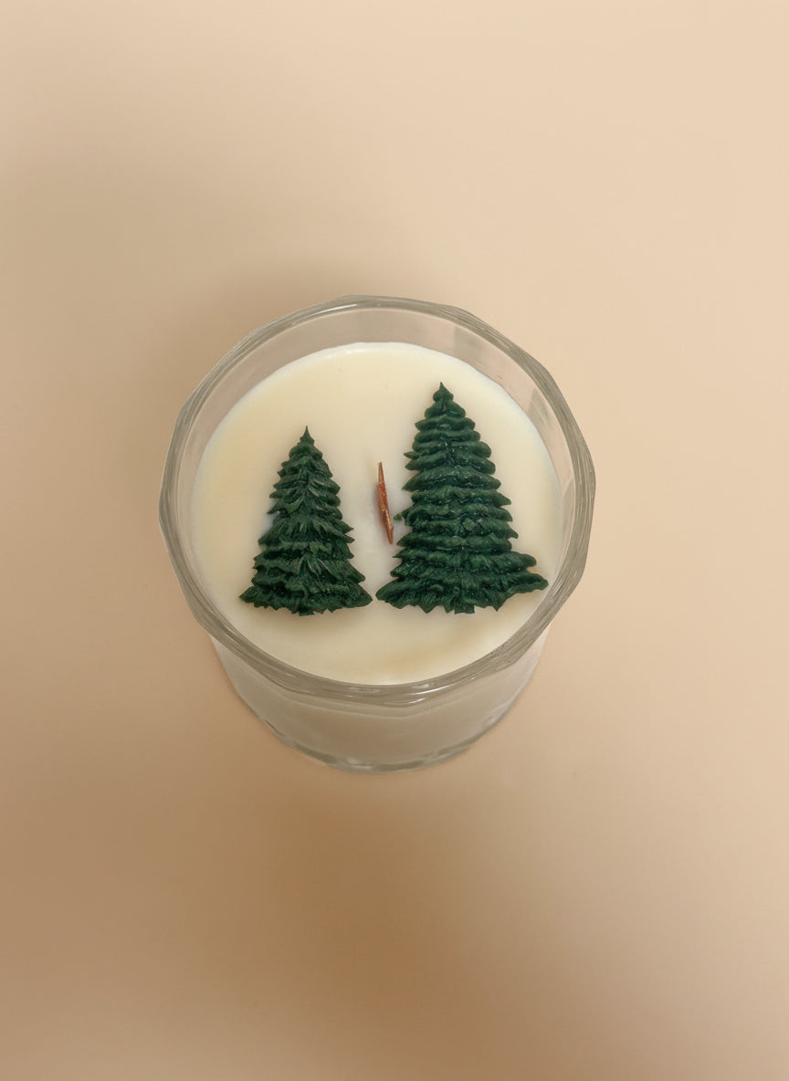 Candle with tree designs on a cream background