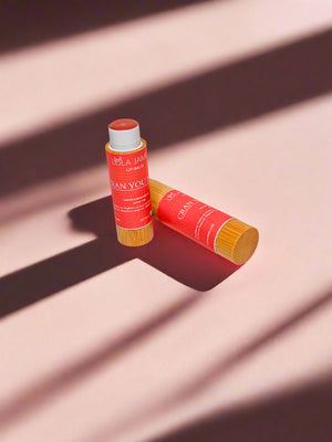 2 lip balms, bamboo containers, pink background with shadows.