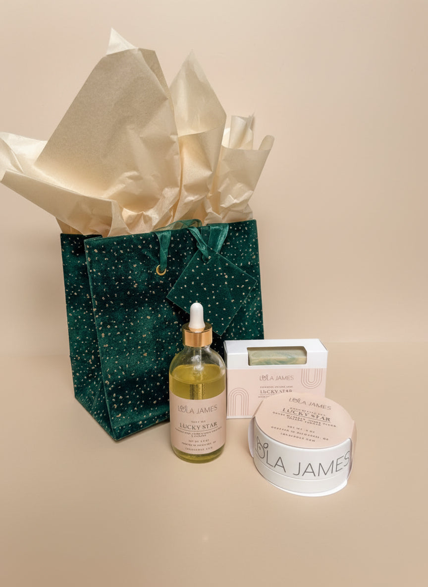 Lucky star gift set with body oil, soap, body butter bar. Green gift bag on a neutral background.