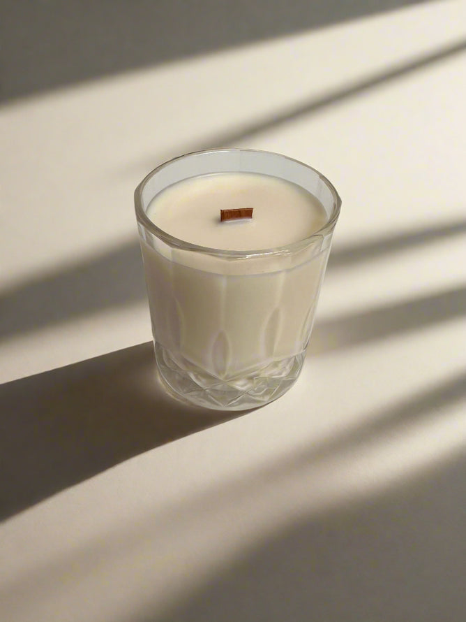 Glass candle with a wooden wick on a light background