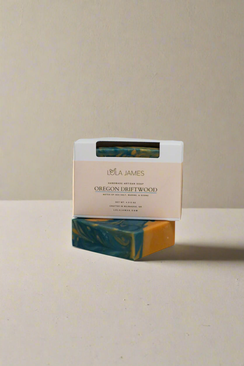 Bar of blue and tan swirled soap with Lola James packaging on a white background