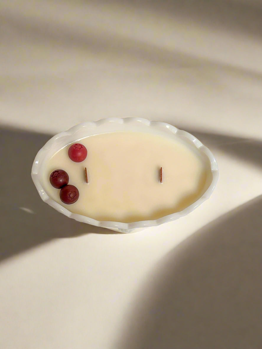 Cranberry embeds in a soy candle with wooden wicks, milk glass.