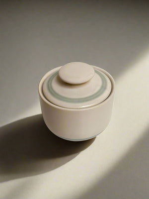 Cream stoneware sugar bowl with lid. Blue line detail.