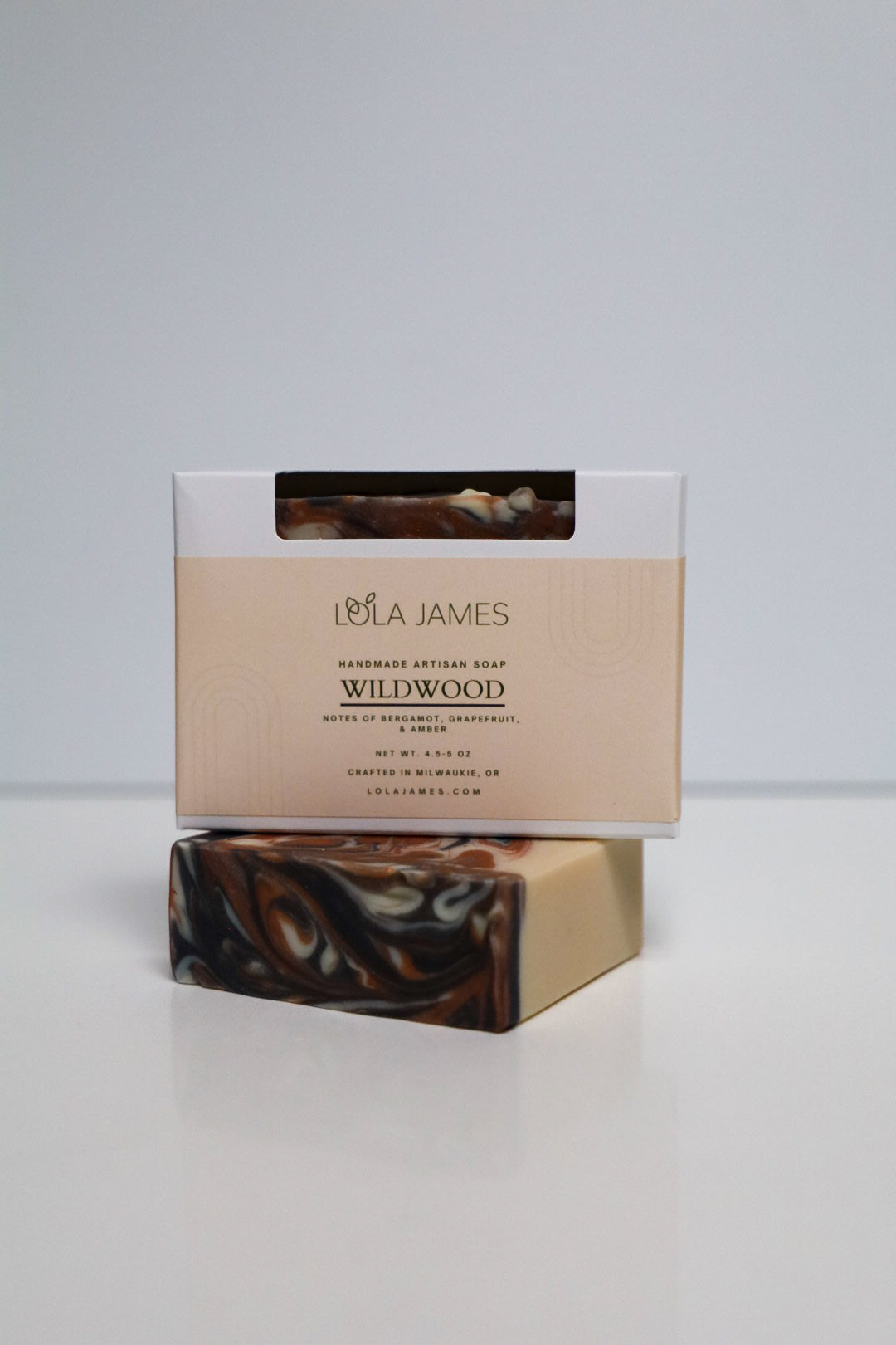 Lola James Wildwood soap bar with packaging on a white background. Soap is white with black and orange swirl pattern.
