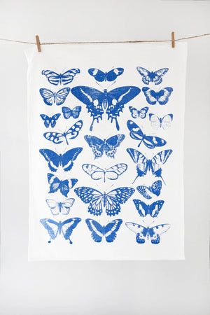 White towel with blue butterfly patterns hanging on a line against a white background
