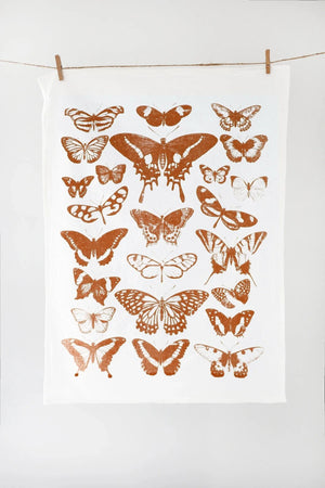 White towel with copper butterfly patterns hanging on a line against a white background