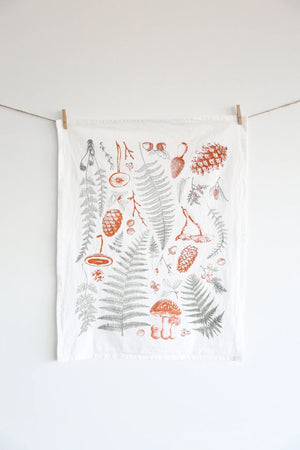 Tea towel with botanical designs hanging on a line against a white background