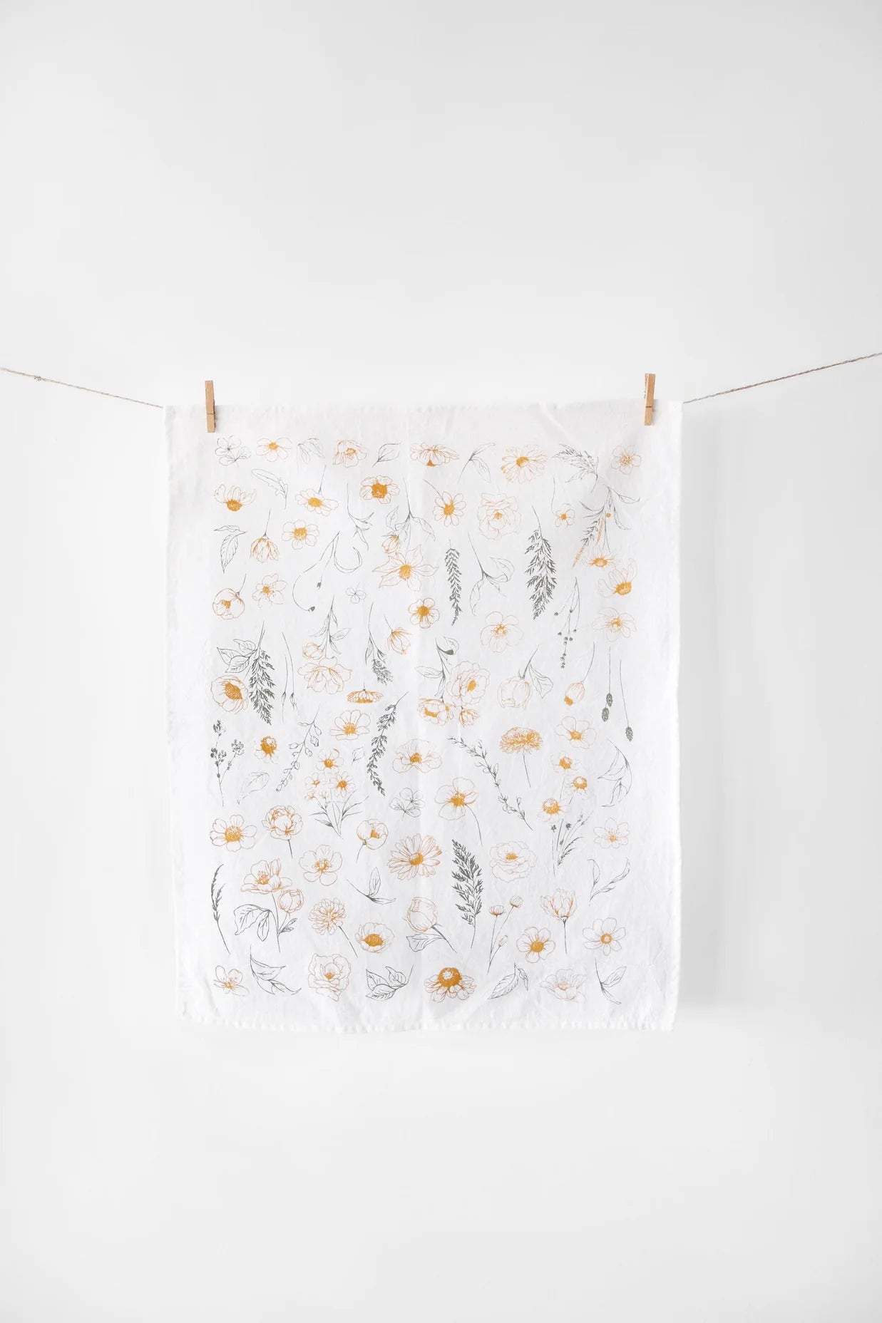Floral-patterned towel hanging on a clothesline against a white background