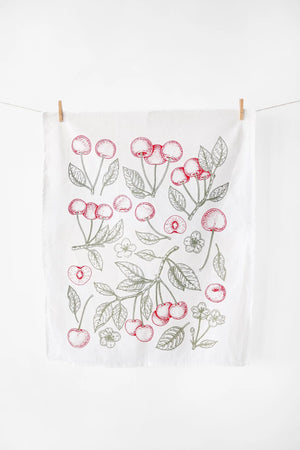 Tea towel with cherry design hanging on a line against a white background